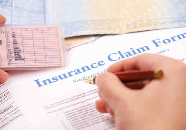 pen in hand filing insurance claim form
